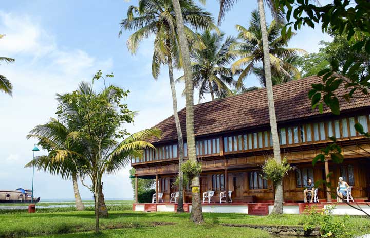 Traditional Kerala architecture beside a palm-lined lake